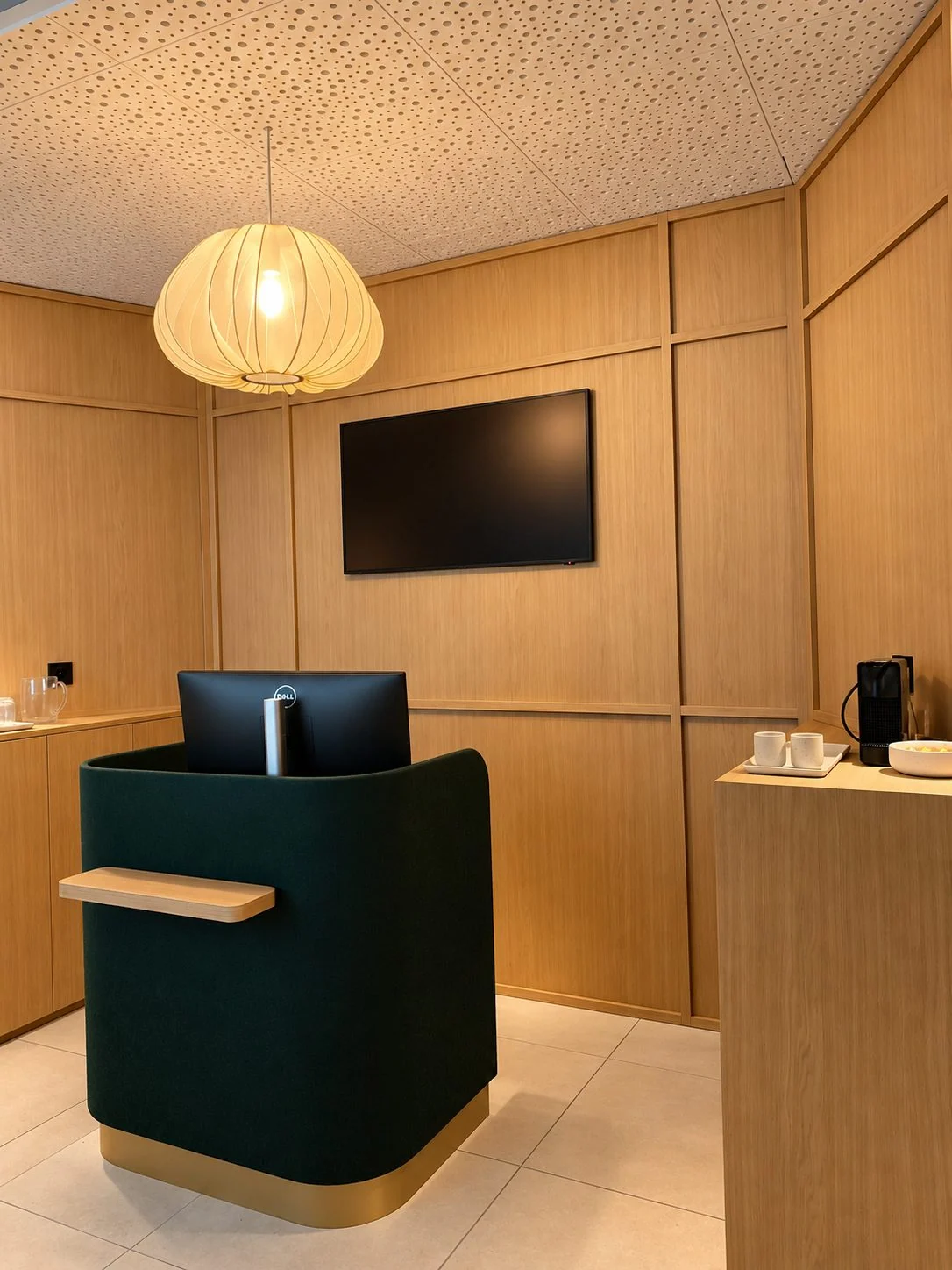 Détail du bureau d'accueil vert et du plafond acoustique