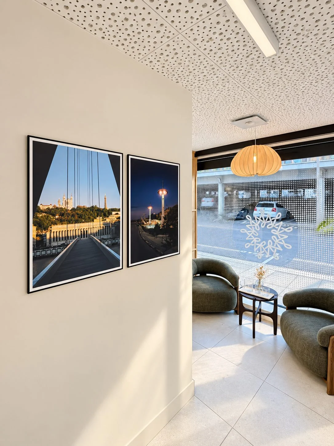 Espace d'attente intimiste avec deux fauteuils verts près de la vitrine